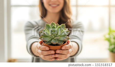 Woman holding a succulent plant in terracotta pot indoors. Woman holding a succulent plant in terracotta pot indoors. 131318317