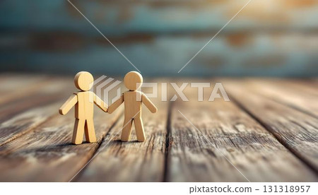 Handcrafted wooden couple holding hands on a table, evoking themes of family and friendship in a rustic background 131318957