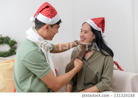 Christmas holiday brings happy loving couple much winter celebration joy at cozy home, man gently adjusting woman warm scarf, truly festive christmas spirit fills day indoors. 131320188