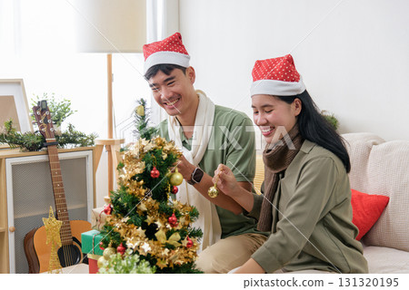 Christmas couple shares love, happy holiday spirit decorating small tree with festive ornaments, enjoying winter celebration, home full of warm christmas joy. Christmas couple shares love, happy holiday spirit decorating small tree with festive ornaments, enjoying winter celebration, home full of warm christmas joy. 131320195