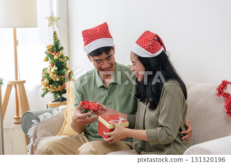 Christmas winter holiday brings happy couple love, sharing gifts by decorated christmas tree, warm home celebration creates unforgettable pure joy and precious memories. Christmas winter holiday brings happy couple love, sharing gifts by decorated christmas tree, warm home celebration creates unforgettable pure joy and precious memories. 131320196