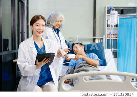 Hospital Ward Male and Male Professional Asian Doctors Talk with a Patient, Give Health Care Advice, Hospital Ward Male and Male Professional Asian Doctors Talk with a Patient, Give Health Care Advice, 131320934