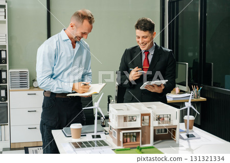 Architects in a business meeting, planning and discussing a modern building model, showcasing teamwork and creativity Architects in a business meeting, planning and discussing a modern building model, showcasing teamwork and creativity 131321334