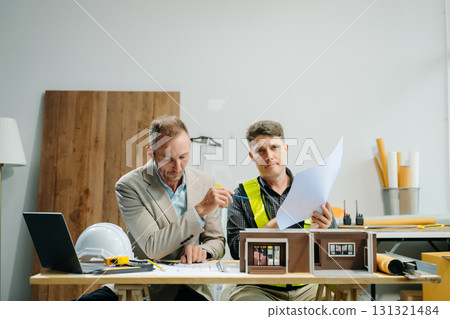 Architects and engineers collaborating on blueprints and models, showcasing teamwork, planning 131321484