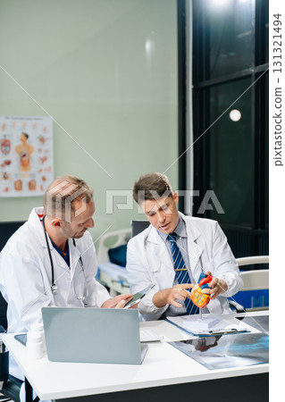 Doctors analyzing an X-ray, collaborating with digital tools in a medical office. Showcasing teamwork, diagnostic Doctors analyzing an X-ray, collaborating with digital tools in a medical office. Showcasing teamwork, diagnostic 131321494