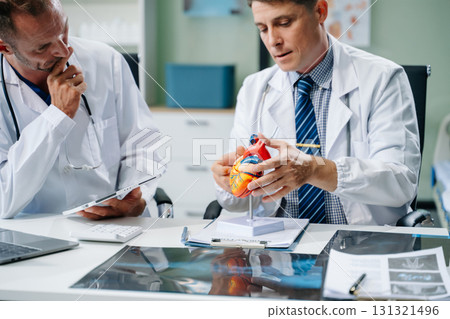 Doctors analyzing an X-ray, collaborating with digital tools in a medical office. Showcasing teamwork, diagnostic Doctors analyzing an X-ray, collaborating with digital tools in a medical office. Showcasing teamwork, diagnostic 131321496
