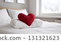 Red knitted heart on a white blanket in a bright bedroom 131321623