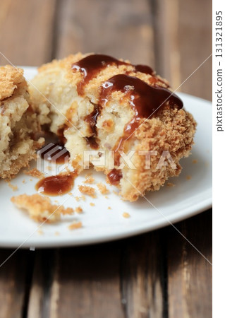 鬆軟的北海道馬鈴薯炸丸子切成兩半,淋上醬汁 鬆軟的北海道馬鈴薯炸丸子切成兩半,淋上醬汁 131321895