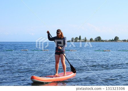 Woman paddleboarding on calm lake 131323306