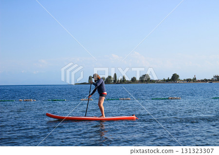 Person paddleboarding on calm water Person paddleboarding on calm water 131323307