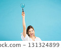 Studio portrait of woman with magnifying glass 131324899