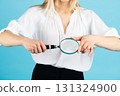 Studio portrait of woman with magnifying glass 131324900