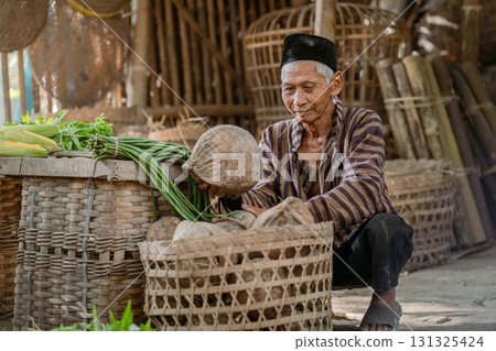 An Elderly Man Dedicated to Sorting Fresh Vegetables in a Traditional Market Setting An Elderly Man Dedicated to Sorting Fresh Vegetables in a Traditional Market Setting 131325424
