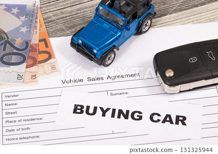 Blue toy car, key, euro banknotes and vehicle sales agreement. Inscription buying car 131325944