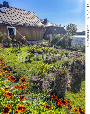 ural garden with blooming flowers, vegetables, and wooden house, summer countryside lifestyle background. High quality photo 131326213