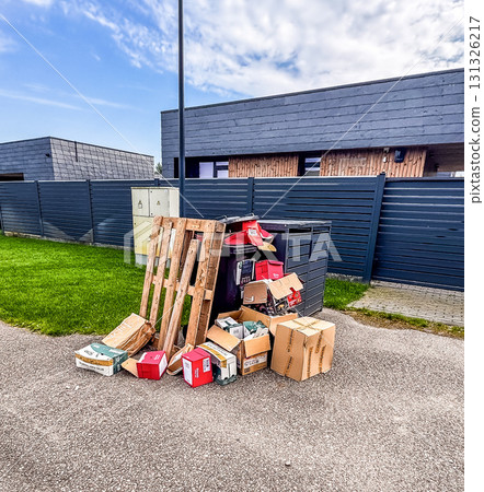 A pile of used cardboard boxes and a wooden pallet left near an outdoor dumpster. Concept of recycling, waste, and environment. High quality photo 131326217
