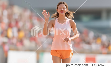 Smiling female runner running on the track after finishing the track and field event Smiling female runner running on the track after finishing the track and field event 131326256