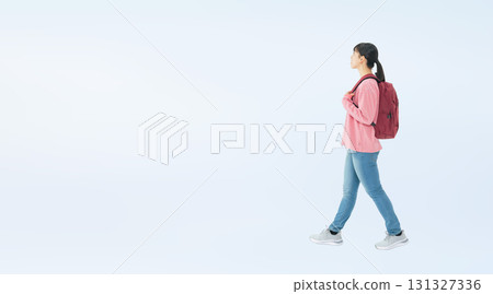 A full-body photo of a teenage woman walking with a backpack A full-body photo of a teenage woman walking with a backpack 131327336