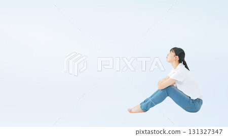 Full-body cropped photo of a teenage woman in casual clothing sitting and looking up Full-body cropped photo of a teenage woman in casual clothing sitting and looking up 131327347