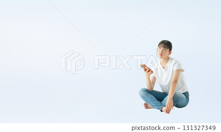 A cutout full-body photo of a teenage woman wearing casual clothing sitting and using a smartphone A cutout full-body photo of a teenage woman wearing casual clothing sitting and using a smartphone 131327349