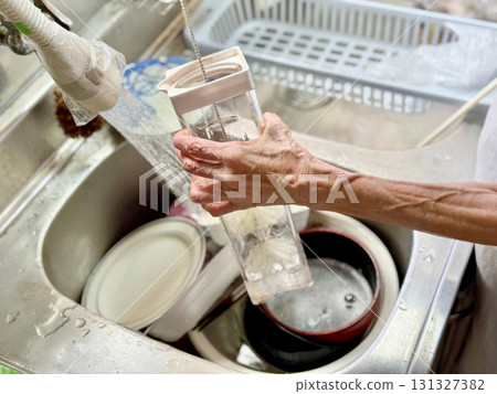 An elderly woman's hands washing a cool pot with a brush 131327382