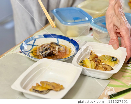 An elderly woman serving food in a pack during meal preparation An elderly woman serving food in a pack during meal preparation 131327391