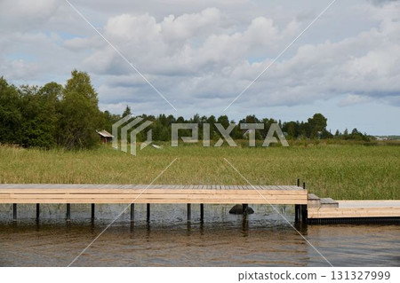 A Serene Dock on a Beautiful Lake Surrounded by Lush Greenery and Gentle Clouds Above A Serene Dock on a Beautiful Lake Surrounded by Lush Greenery and Gentle Clouds Above 131327999