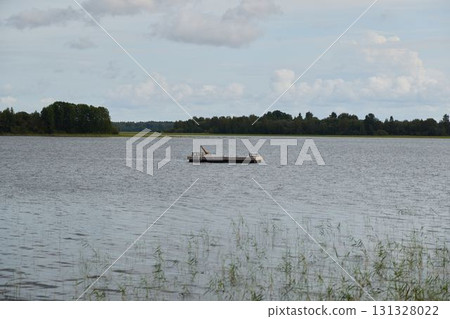 A Beautiful and Serene Scene of a Tranquil Lake Featuring a Boat Beneath a Gorgeous Cloudy Sky A Beautiful and Serene Scene of a Tranquil Lake Featuring a Boat Beneath a Gorgeous Cloudy Sky 131328022