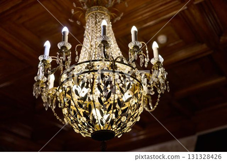An Elegant and Stunning Crystal Chandelier with Beautiful Golden Accents in a Luxurious Setting An Elegant and Stunning Crystal Chandelier with Beautiful Golden Accents in a Luxurious Setting 131328426