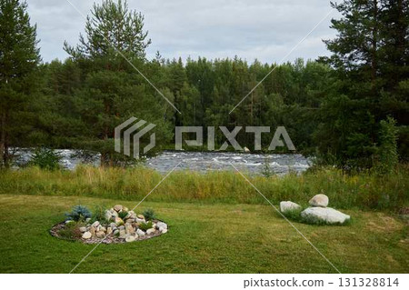 A Serene Riverbank Landscape featuring Lush Greenery and Beautiful Floral Embellishments 131328814