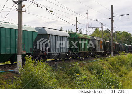 Freight train cars line the tracks in a vibrant green landscape, highlighting natures beauty Freight train cars line the tracks in a vibrant green landscape, highlighting natures beauty 131328931