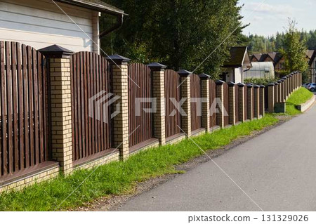 A Beautifully Crafted Elegant Wooden Fence Alongside a Scenic and Picturesque Residential Road 131329026