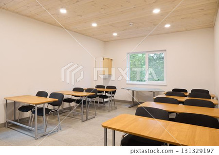 A modern classroom interior featuring desks, ample natural light, and a welcoming atmosphere A modern classroom interior featuring desks, ample natural light, and a welcoming atmosphere 131329197