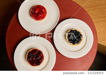 Savor the Deliciously Beautiful Fruit Tarts with Fresh Berries Presented on Elegant Plates 131329353