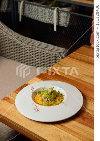 An Elegant and Artistic Plate of a Gourmet Meal Beautifully Presented on a Wooden Table 131329430