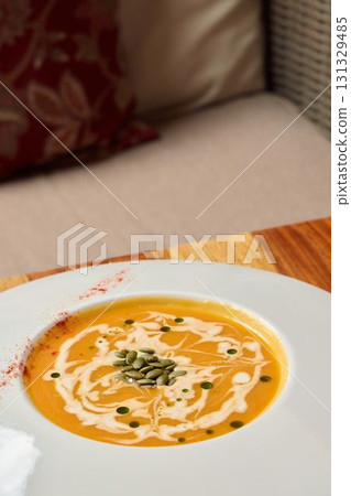 Indulge in a delightful bowl of creamy pumpkin soup, attractively and beautifully garnished Indulge in a delightful bowl of creamy pumpkin soup, attractively and beautifully garnished 131329485