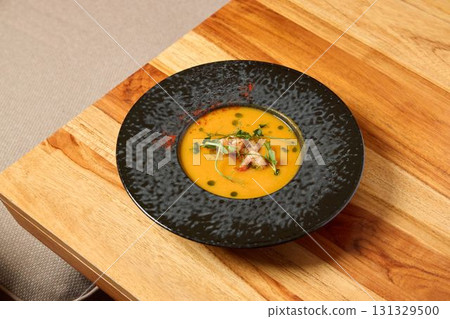 Savor the flavor of a deliciously creamy soup elegantly served in a stylish black plate Savor the flavor of a deliciously creamy soup elegantly served in a stylish black plate 131329500