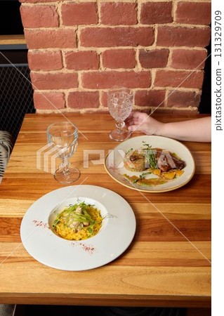 Enjoyable and Delicious Dishes Beautifully Served on a Wooden Table in a Cozy Restaurant Enjoyable and Delicious Dishes Beautifully Served on a Wooden Table in a Cozy Restaurant 131329709