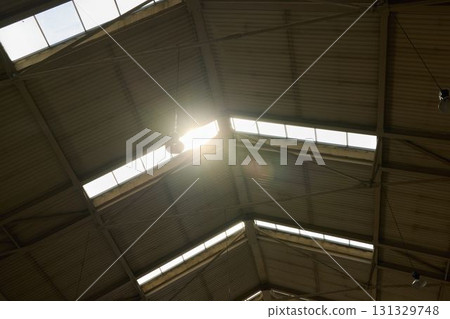 Sunlight streams through the industrial roof, creating a captivating light and shadow interplay Sunlight streams through the industrial roof, creating a captivating light and shadow interplay 131329748