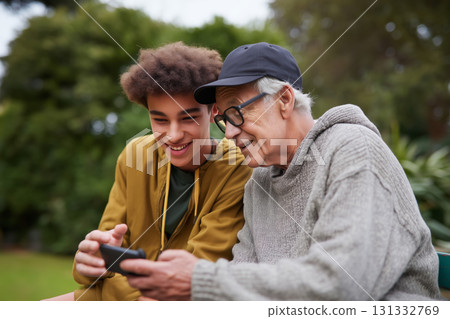 Teen teaches elder how to use smartphone during a sunny afternoon outdoors 131332769