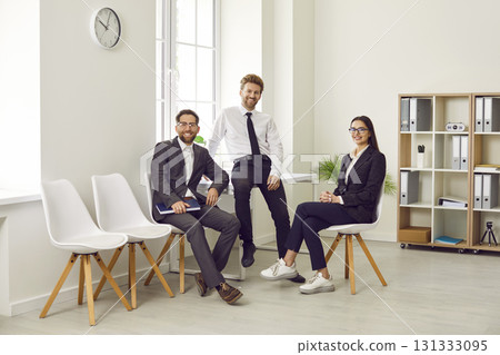 Group of business people of three looking at the camera and smiling at the workplace. 131333095