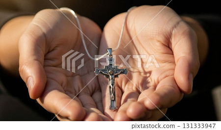 Two hands holding a small metal cross tenderly. 131333947