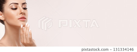 Beautiful smiling woman with healthy smooth facial clean skin applying cosmetic cream and touch own face. Model with Beauty face. Skin care. Panorama Beautiful smiling woman with healthy smooth facial clean skin applying cosmetic cream and touch own face. Model with Beauty face. Skin care. Panorama 131334146