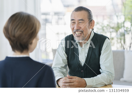 A man in his 70s talking face to face with a businesswoman A man in his 70s talking face to face with a businesswoman 131334939