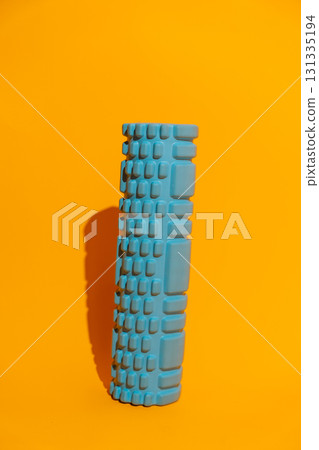Textured blue foam roller standing on orange studio background active recovery gear with copy space Textured blue foam roller standing on orange studio background active recovery gear with copy space 131335194
