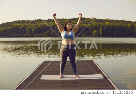 Fat woman in sportswear do winner's gesture holding hands up in fists standing outdoor. Fat woman in sportswear do winner's gesture holding hands up in fists standing outdoor. 131335230