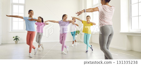 Happy children girls training modern dance moves together in studio with choreographer. Happy children girls training modern dance moves together in studio with choreographer. 131335238