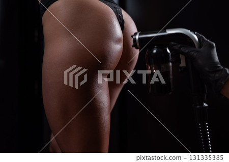 The master applies tinting paint on the back of a woman. Instant tanning treatment. 131335385