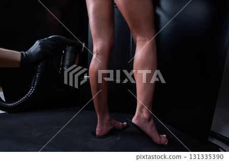The master applies tinting paint to the woman's legs. Instant tanning procedure The master applies tinting paint to the woman's legs. Instant tanning procedure 131335390