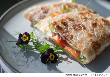 A flatbread stuffed with fish and cheese served in a cafe. Quesadilla. A flatbread stuffed with fish and cheese served in a cafe. Quesadilla. 131335424